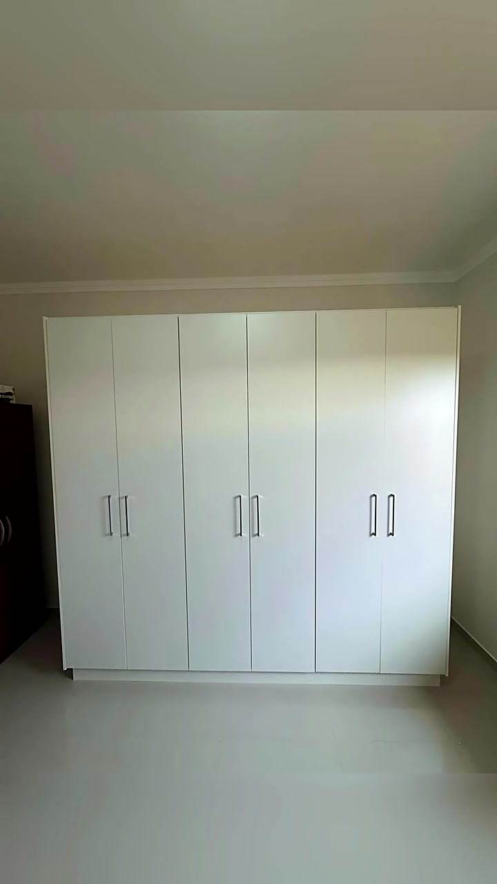 Vista das portas brancas e dos puxadores do guarda-roupa planejado
