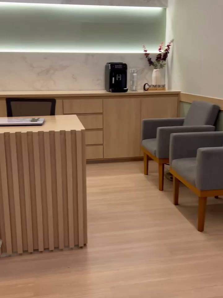 Recepção da clínica Clinifisio com painel ripado em madeira clara e iluminação indireta