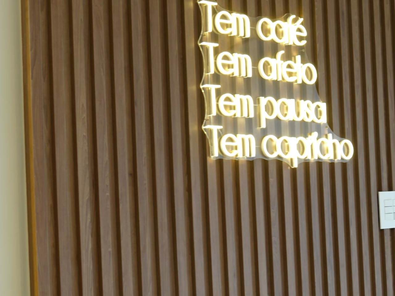 Cafeteria em Botelhos com painel ripado, neon, banco estofado e balcão planejados pela JN
